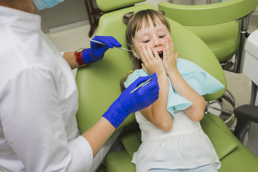 Pediatric dentist explaining dental care to a young child in a bright clinic